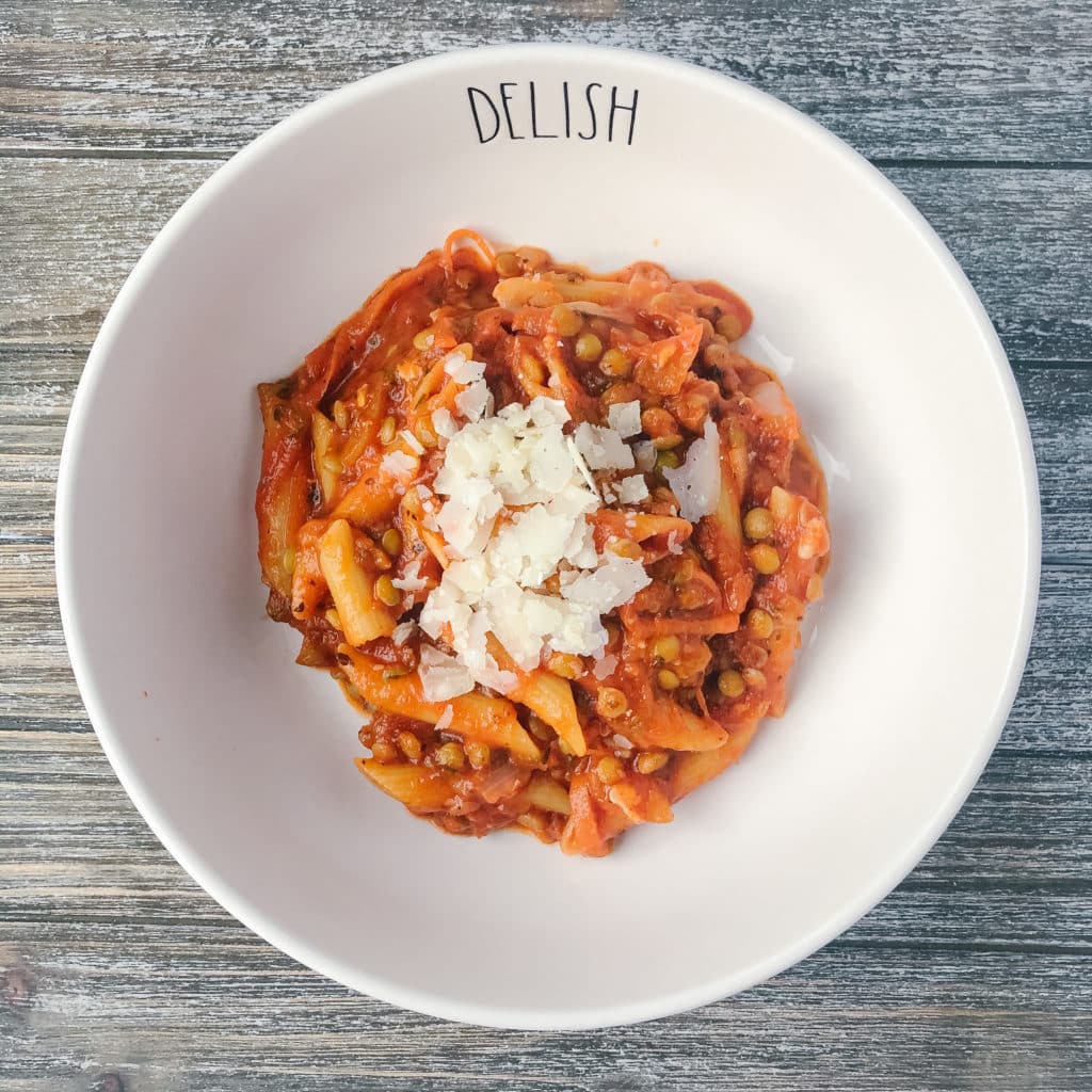 Finished lentil pasta in a serving bowl with parmesan cheese