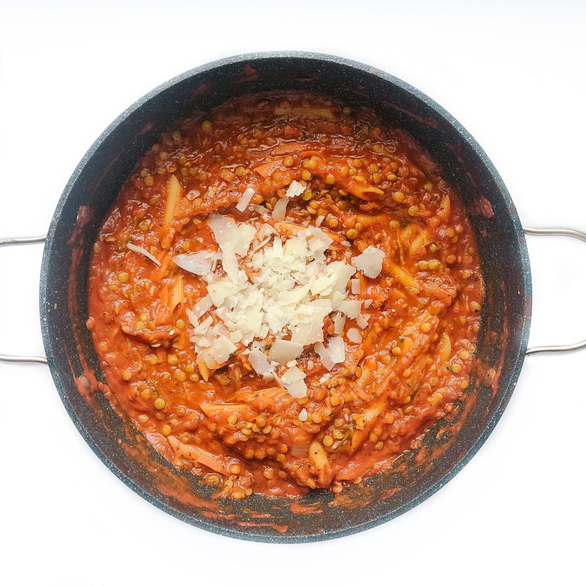 Cooked lentil pasta in a pan with parmesan cheese