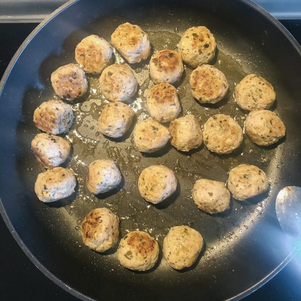 pesto chicken meatballs cooking in pan with oil 