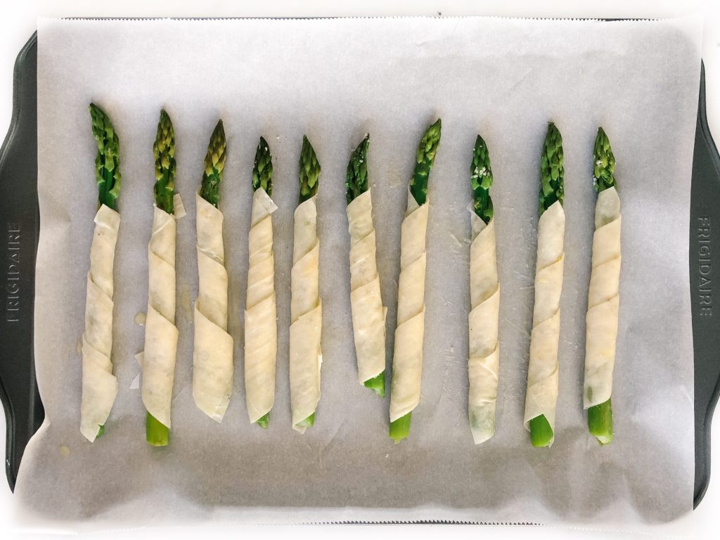 lemon parmesan phyllo wrapped asparagus on a sheet pan before baking