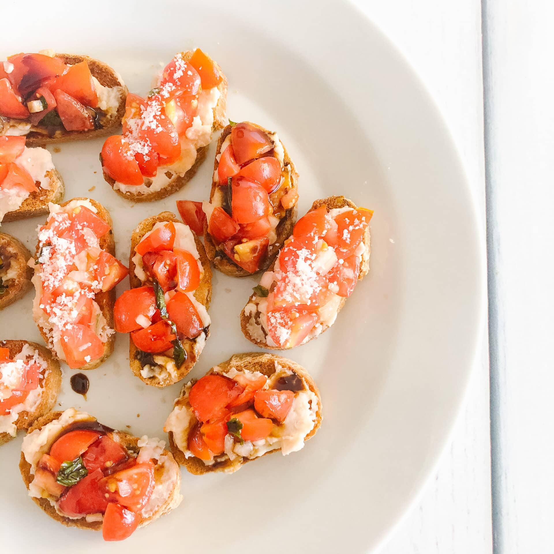 bruschetta with white bean spread topped with balsamic glaze and parmesan