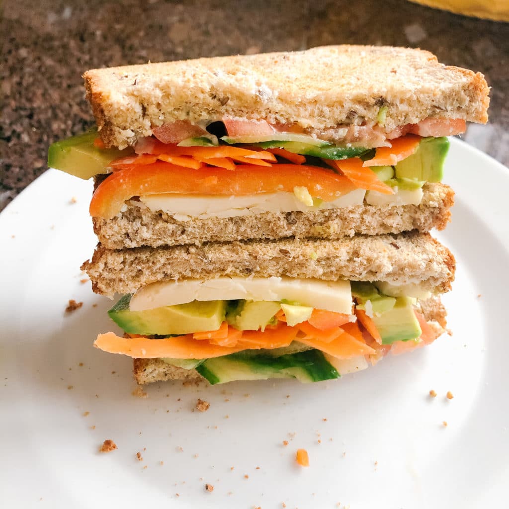 easy veggie loaded sandwich stacked on a white plate