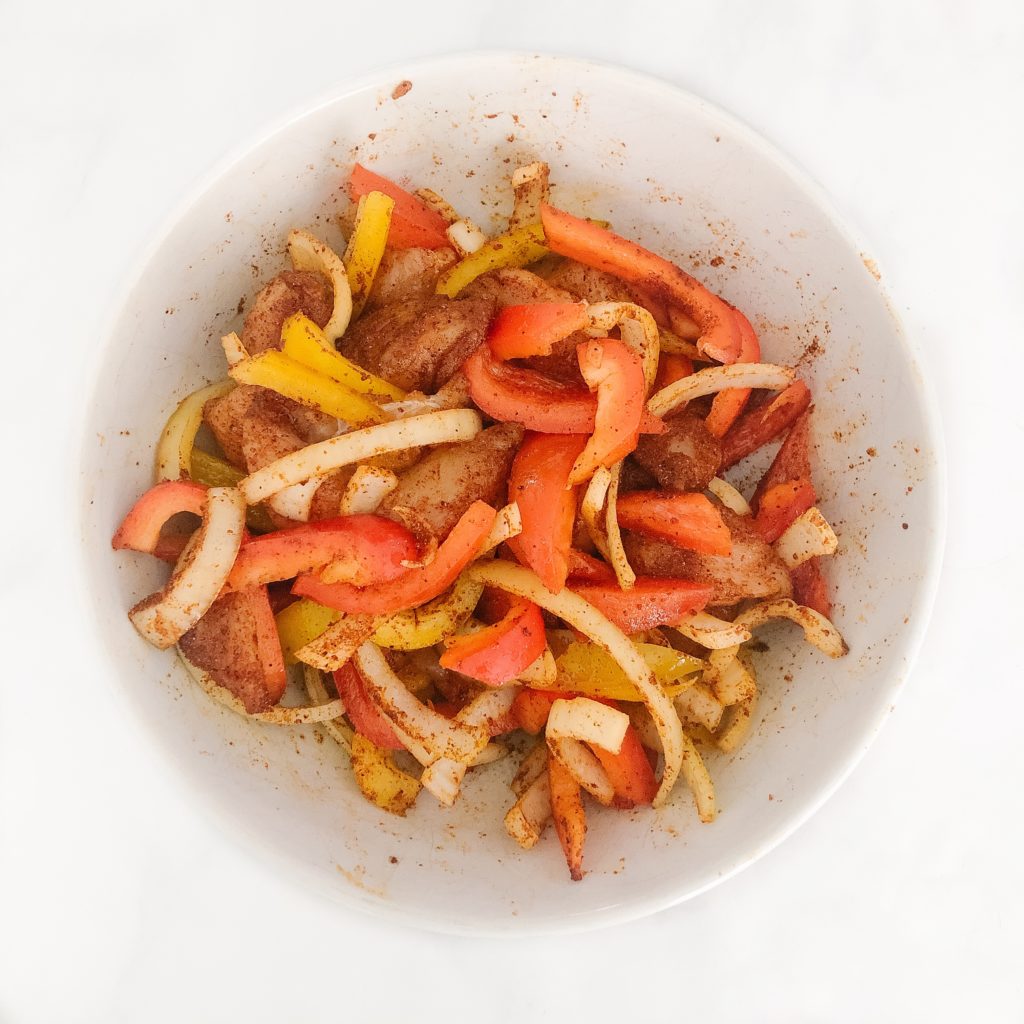 chicken, peppers, onion, spices in a bowl